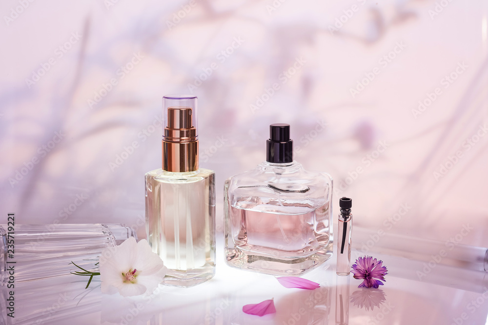 Different perfume bottles and sampler with plants on a pink floral background. Selective focus. Perfumery collection, - obrazy, fototapety, plakaty 