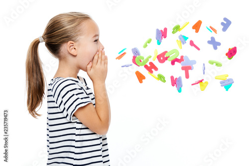 Cute little girl in stripped T-shirt shouting out alphabet letters. Speech therapy concept over white background. photo