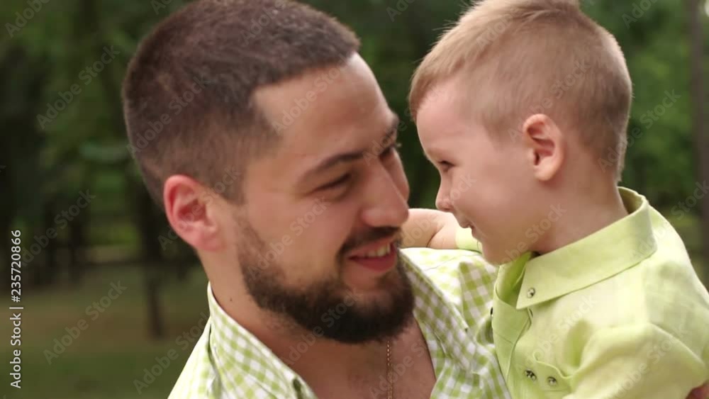 Portrait of a happy bearded man with his son in the Park in the summer. Father and son play in the summer Park in warm Sunny weather. Close-up. Slow motion. Portrait of a happy bearded man with his son in the Park in the summer. Father and son play in the summer Park in warm Sunny weather. Close-up. Slow motion.