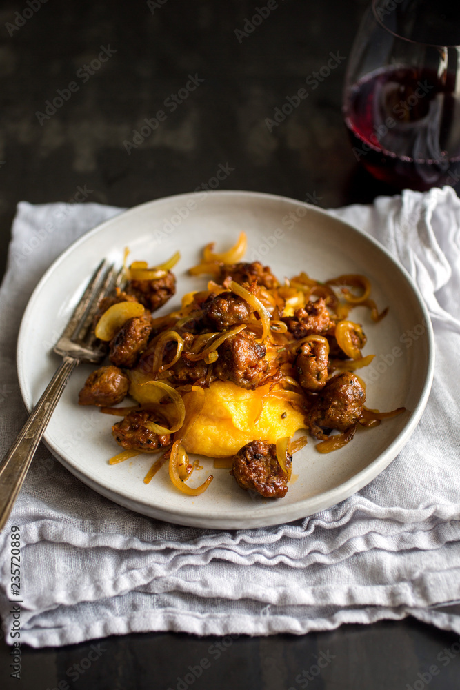 Close up of squash polenta with sausage and onion served on plate Close up of squash polenta with sausage and onion served on plate