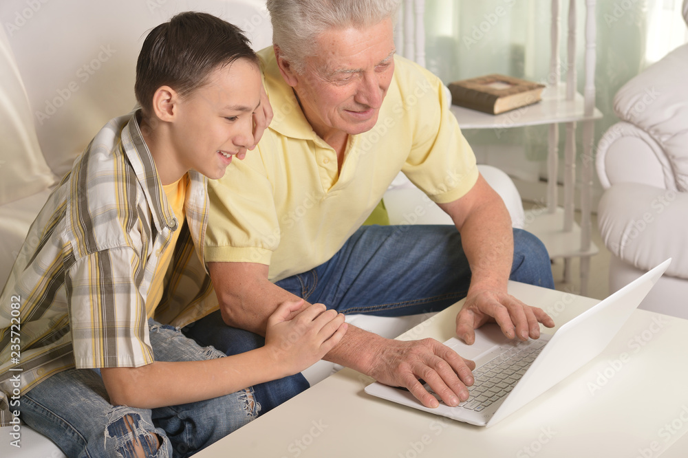 Grandfather with grandson using laptop at home