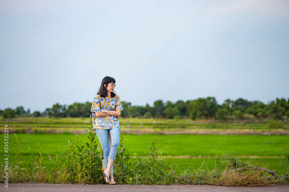 Beautiful young Asian woman on the road with rice field in the background