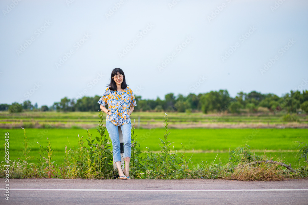 Beautiful young Asian woman on the road with rice field in the background