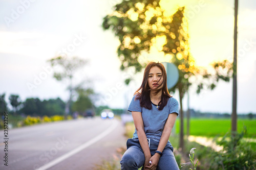 Fototapeta Naklejka Na Ścianę i Meble -  Beautiful young Asian woman on the side road in the evening