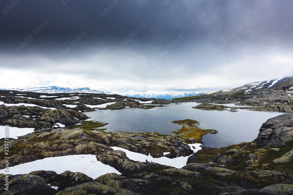 Typical norwegian landscape with snowy mountains and clear lake near the Trolltunga rock - most spectacular and famous scenic cliff in Norway