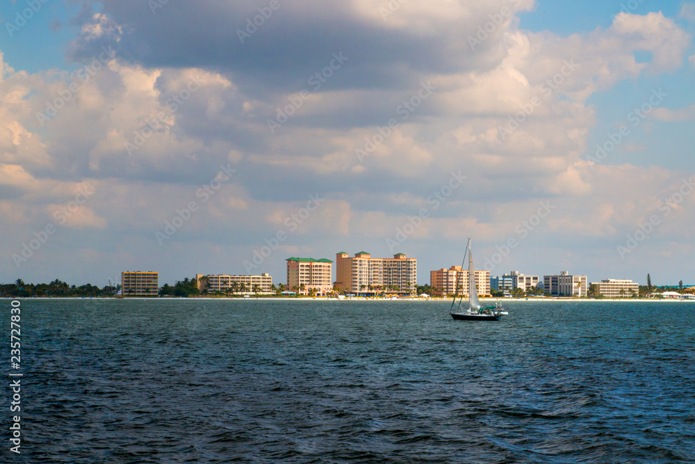 Coastal scenery of Fort Myers beach at Estero Island in Florida, view from boat through the sea waters to the beach with beachfront hotel buildings