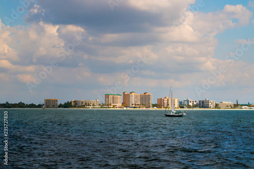 Coastal scenery of Fort Myers beach at Estero Island in Florida, view from boat through the sea waters to the beach with beachfront hotel buildings photo