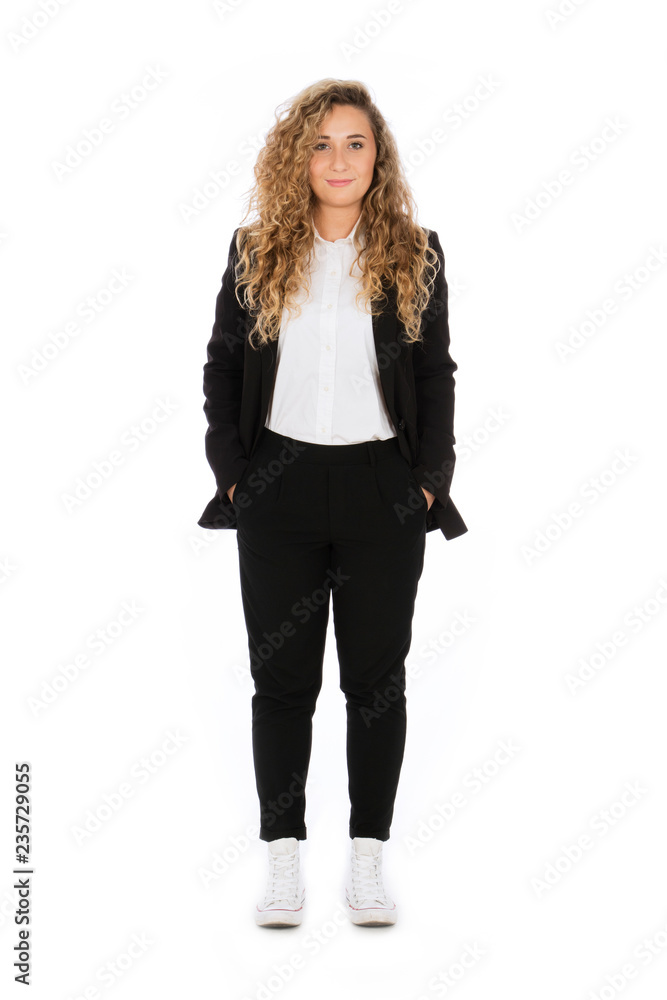 Smiling girl with curly blonde hair, she is standing with hands in pockets, wearing a black suit and white shirt and sneakers Smiling girl with curly blonde hair, she is standing with hands in pockets, wearing a black suit and white shirt and sneakers