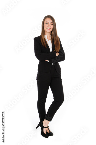 Smiling girl with long hair, she is standing with her arms crossed, wearing a black suit and white shirt and shoes with high heels