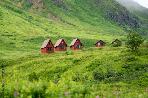 Foto Abandoned red cabins sit in the green lush mountains of Alaska’s Hatcher Pass near Independence Mine