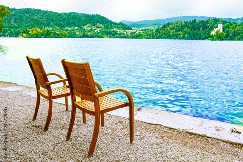 Two chairs on the shore of the resort lake. View of the mountains and the forest.