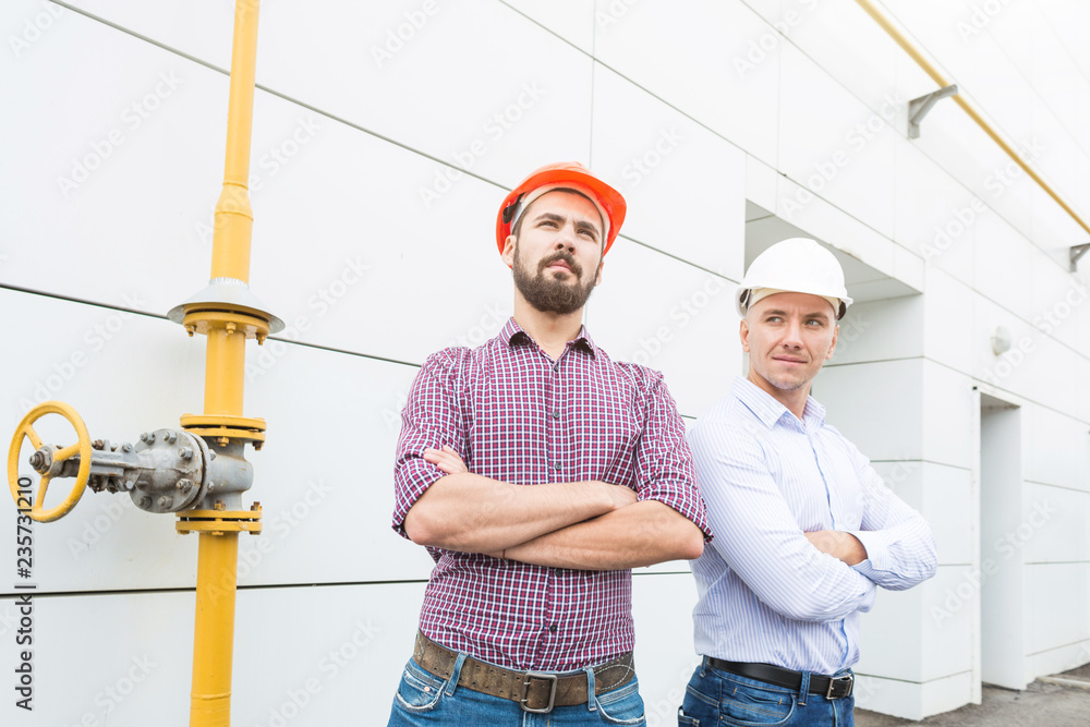two male engineers in helmets on the building background two male engineers in helmets on the building background