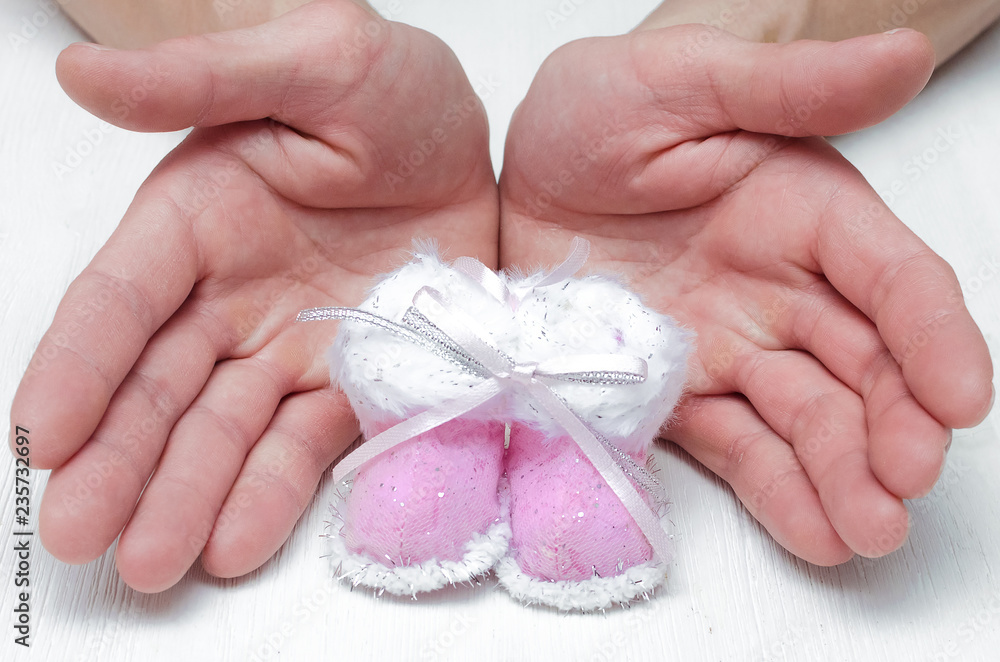 Newborn baby booties Christmas toy in father hands on white background. Newborn baby booties Christmas toy in father hands on white background.