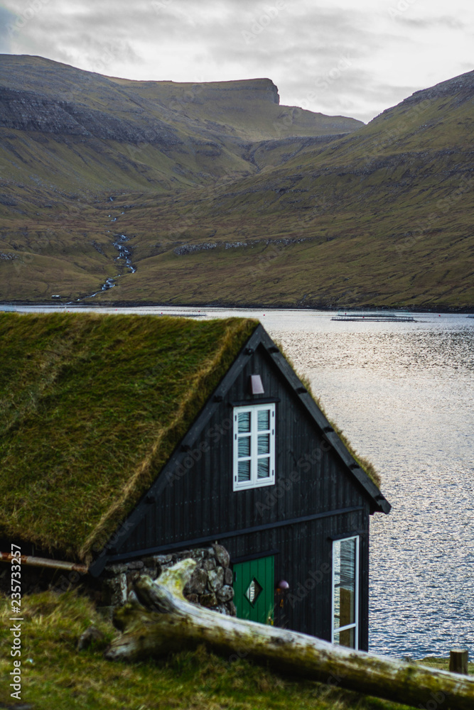 Scenic landscape view of traditional historic stone wooden house/building with grass (turf) roof in Gasadálur village, Vágar Island. Tourist popular attraction/place in Faroe Islands (Denmark) Scenic landscape view of traditional historic stone wooden house/building with grass (turf) roof in Gasadálur village, Vágar Island. Tourist popular attraction/place in Faroe Islands (Denmark)