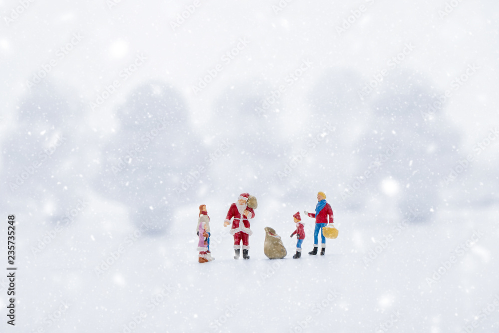 Miniature people in Christmas Theme. Santa Claus giving Christmas gift to children on Christmas day Miniature people in Christmas Theme. Santa Claus giving Christmas gift to children on Christmas day