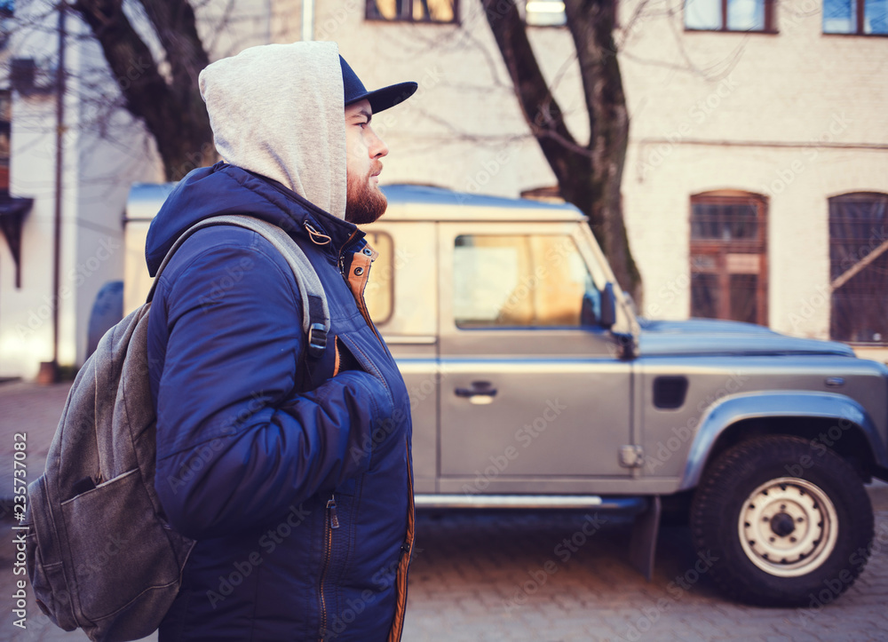 Portrait of traveller man with bag near car outdoor in city street Portrait of traveller man with bag near car outdoor in city street