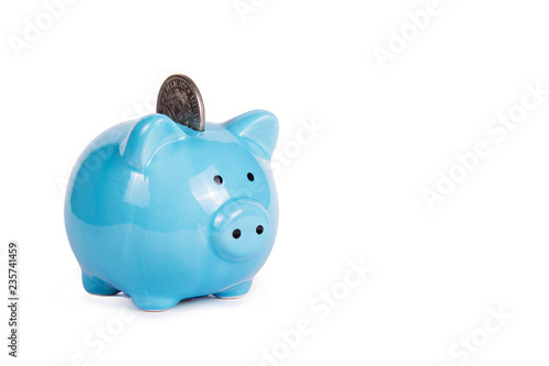 Blue piggy bank on white background. Copy space. Piggy bank and coin.