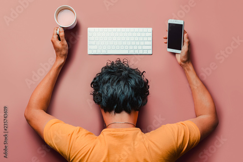 Flat lay man with burn out sleeps on table with keyboard,smartphone and coffee. photo