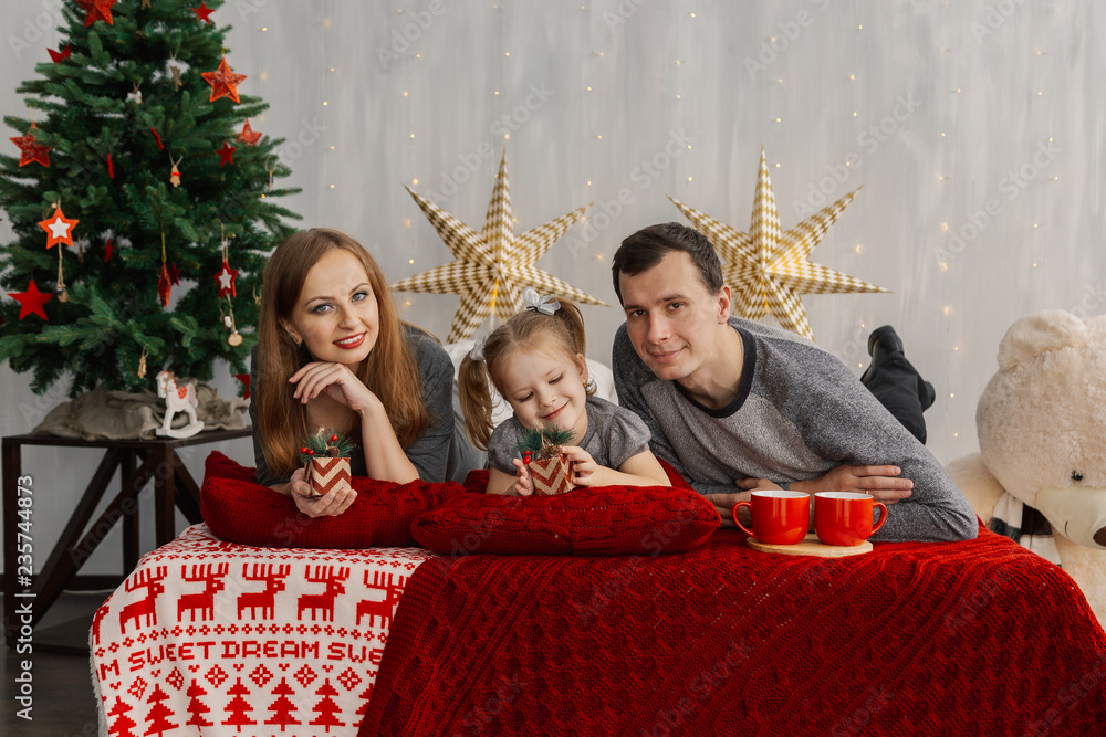 Happy family on bed on a bright Christmas morning. New Year 2019. Happy family on bed on a bright Christmas morning. New Year 2019.