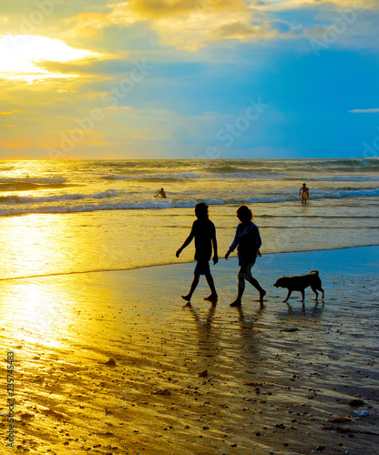 People walking dog beach. Bali