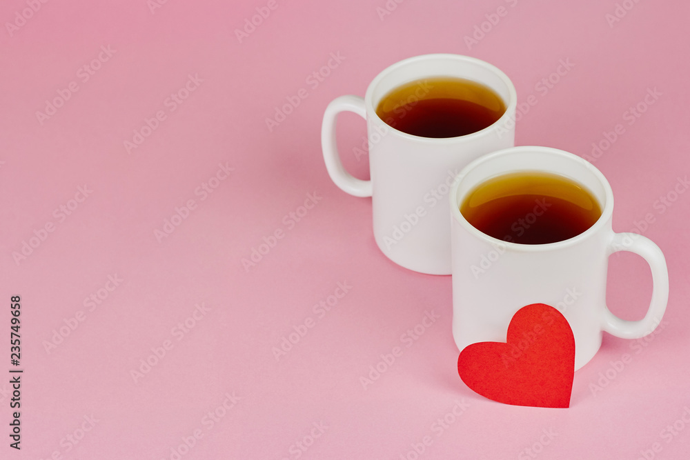 Red paper heart and two white cups on pink background. Valentine's day, love, wedding concept Red paper heart and two white cups on pink background. Valentine's day, love, wedding concept