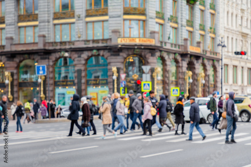 Fototapeta Naklejka Na Ścianę i Meble -  in the blur of the intersection where a group of people cross the street on the background of the building