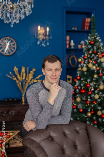 Very handsome man is standing by the chair in the New Year's room. © combo1982