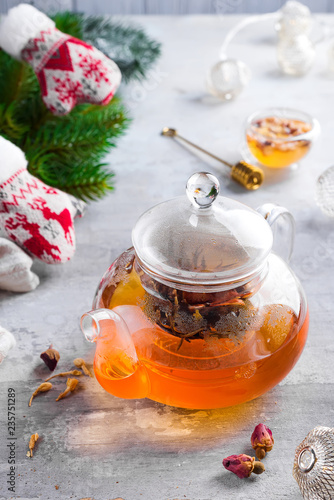 Glass teapot with flowers tied tea, Hot tea in glass teapot and honey with metal honey stick on stone background, Christmas concept