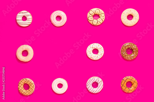 Texture of multicolored donuts on pink background. Sweets and food