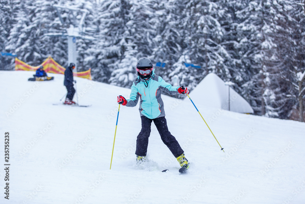 Teenage girl in helmet on the slope at ski resort