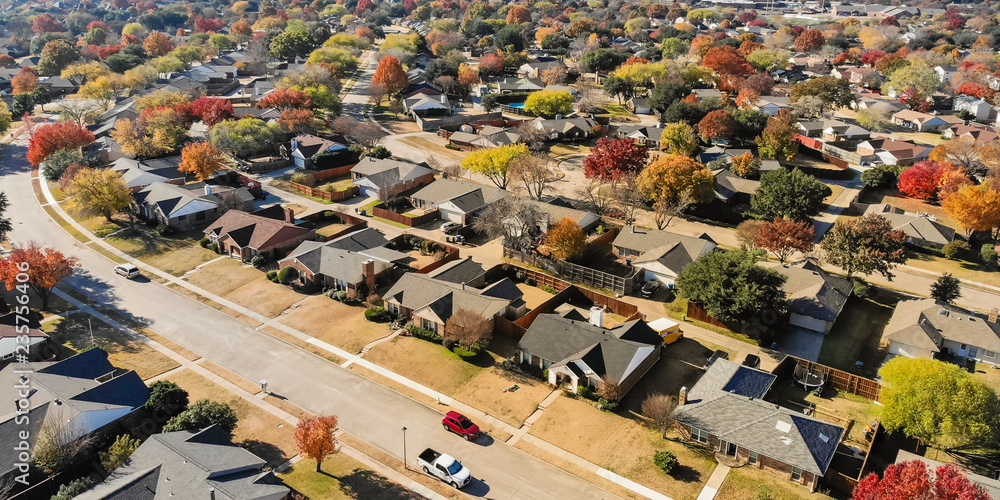 Obraz premium Panorama top view beautiful neighborhood in Coppell, Texas, USA in autumn season. Row of single-family home with attached garage, garden, surrounded by colorful fall foliage leaves under blue sky