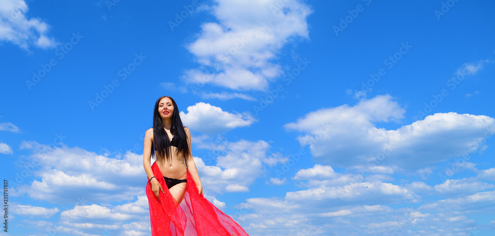 Young brunette girl in black lingerie with red canvas on sky background with clouds. Young brunette girl in black lingerie with red canvas on sky background with clouds.