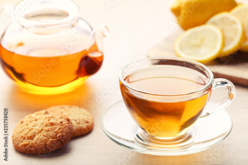 Cup of tea with cookies and teapot on wooden table