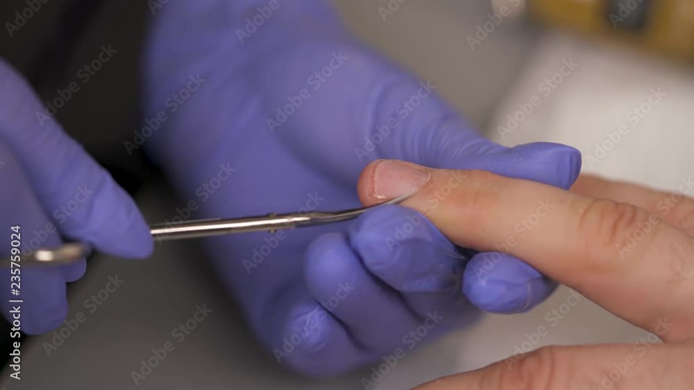 Close-up of manicurist cutting cuticles on the man fingernails using a nail scissors. Close-up of manicurist cutting cuticles on the man fingernails using a nail scissors.