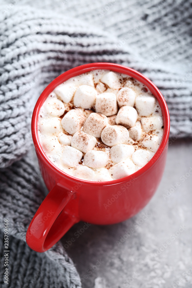 Cappuccino with marshmallows in cup and knitted scarf on grey woodent able Cappuccino with marshmallows in cup and knitted scarf on grey woodent able