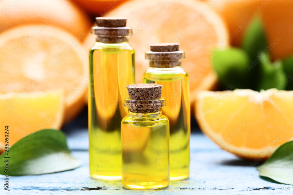 Orange oil in bottles with green leafs on blue wooden table Orange oil in bottles with green leafs on blue wooden table