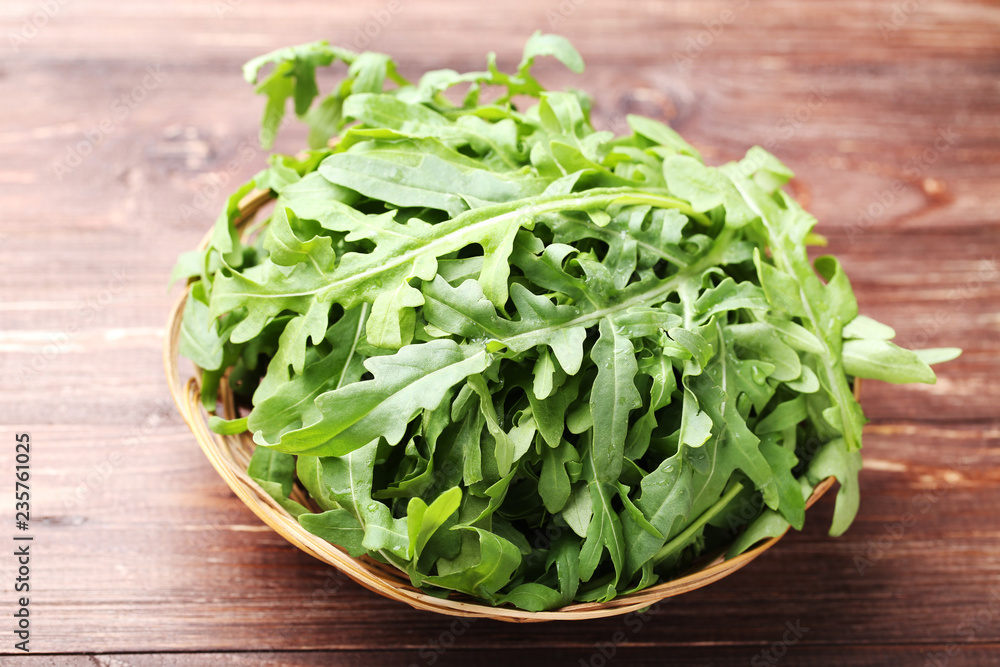 Green arugula leafs in basket on brown wooden table Green arugula leafs in basket on brown wooden table