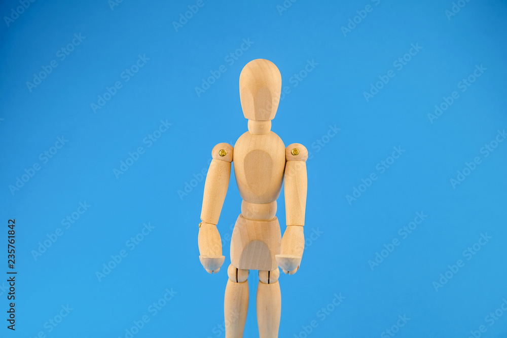 Wooden dummy holds two hands in front of itself on blue background Wooden dummy holds two hands in front of itself on blue background