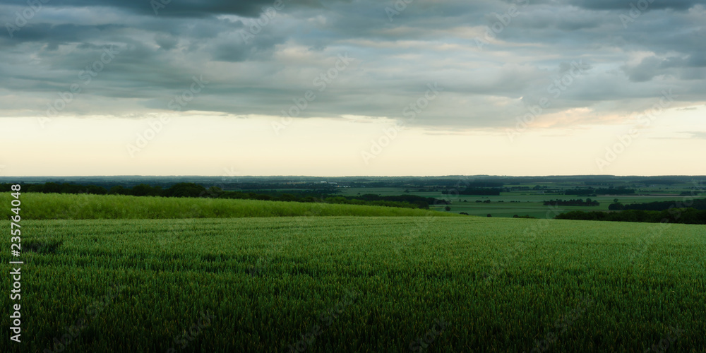 rolling hills with dramatic sky over farmland greens and greys rolling hills with dramatic sky over farmland greens and greys