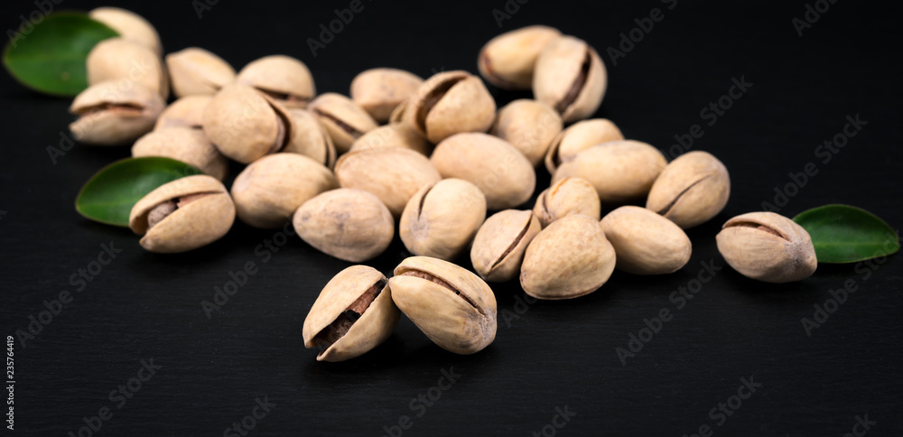 Handful of pistachios on a black background - healthy snack.