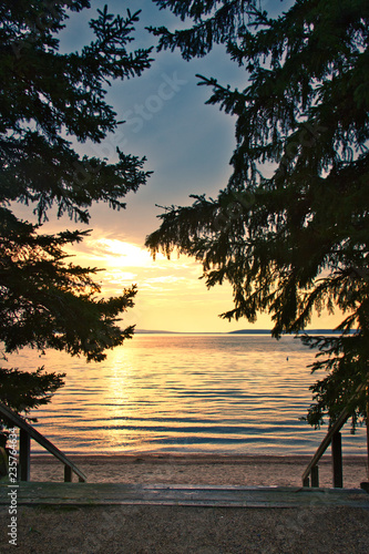 Stairs leading down to a beach with the sun setting over Waskesiu Lake in Prince Albert National Park of Canada. photo