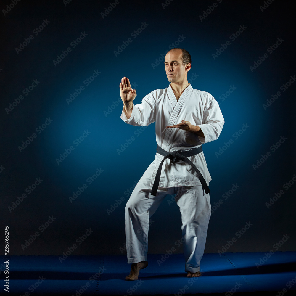 Athlete doing formal exercises on blue tatami Athlete doing formal exercises on blue tatami