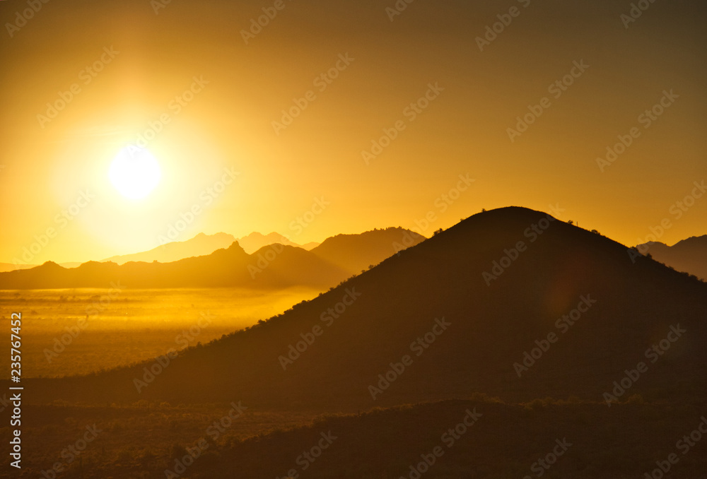 The sun rising over the mountains of the Arizona desert with natural warm hues.