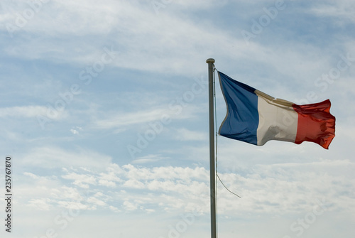 flag of france, blue, red and white, flying in the wind, worn and broken, sky with clouds, sun, patriotism, state, europe, government, freedom, equality, politics.