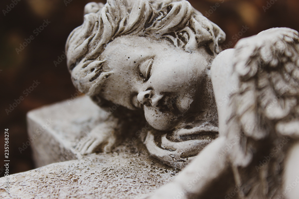 Closeup of putto or child angel figurine sleeping on a cross