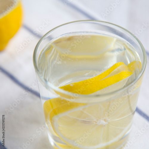 Water with lemon in glass on cloth, side view. Diet weight loss and healthy eating. Detox drink.