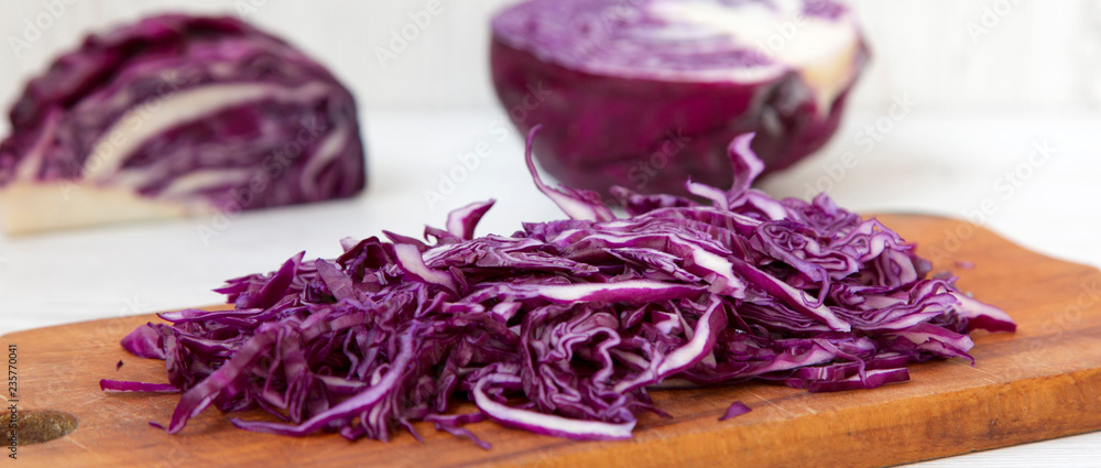 Obraz premium Chopped red cabbage on rustic cutting board, side view. Close-up.