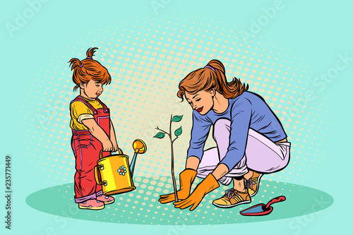 mother and daughter working in the garden, planting a seedling