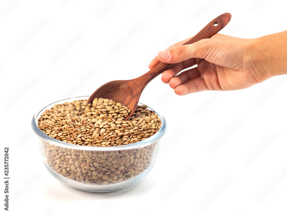 dry lentil in glass bowl with wooden spoon in the hand isolated on white background dry lentil in glass bowl with wooden spoon in the hand isolated on white background