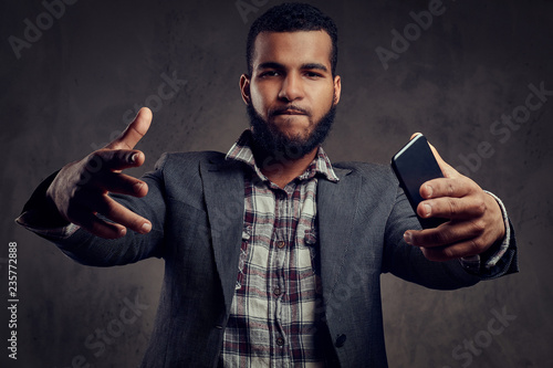 African-American guy is posing next to a dark textured wall.